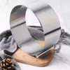 A stainless steel cake ring on a wooden board with a gray scarf and a pinecone. Podgląd zdjęcia produktu