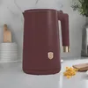 A burgundy electric kettle with a gold logo is placed on a kitchen counter. Produktbild-Vorschau