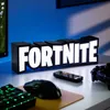 A Fortnite logo lamp sits on a desk next to a computer mouse, keyboard, and controller. Anteprima dell’immagine prodotto