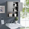 A gray bathroom cabinet with double doors is mounted on a gray wall above a white sink. The cabinet is open, revealing several bottles and containers. A window with green foliage is visible in the background. Podgląd zdjęcia produktu