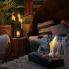 An outdoor seating area at dusk, with candles and a small fireplace providing warm lighting. Náhľad obrázku produktu