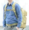 A person wearing a blue patterned shirt and a tactical backpack. Náhled obrázku produktu