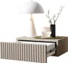 A white lamp, a black vase with branches, and a glass of water are placed on a bedside table with an open drawer. Produktbild-Vorschau