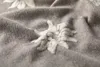 A close-up of a textured fabric with an embroidered Edelweiss flower. Produktbild-Vorschau