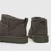 A close-up view of the back of two grey UGG boots with green soles. Voir les images du produit