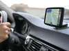 A person's hand is on the steering wheel of a car, with a GPS navigation device mounted on the dashboard. Podgląd zdjęcia produktu
