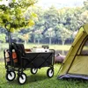 A black folding wagon filled with items is parked on grass next to a green tent, with trees and a body of water in the background. Náhled obrázku produktu