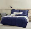 A neatly made bed with navy blue bedding, pillows, and a throw blanket. Produktbild-Vorschau