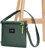 A green Pacsafe crossbody bag is shown against a light wooden background. Produktbild-Vorschau
