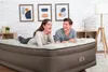 A couple is lying on an air mattress in a room with artwork on the wall. Produktbild-Vorschau