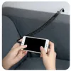 Hands holding a white smartphone connected to a coiled black cable, resting on a gray sofa. Anteprima dell’immagine prodotto