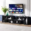 A modern living room setup featuring a wall-mounted TV above a black modular TV stand filled with decorative items. Náhled obrázku produktu