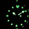 A close-up view of a watch face in the dark, with luminous markers and hands. Produktbild-Vorschau