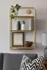 A gold wall shelf with various decorative items and books. Produktbild-Vorschau