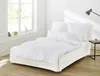 A white bed with white bedding is shown in a bright room with a window. Produktbild-Vorschau