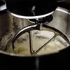 A close-up of a stand mixer with a beater in a bowl of batter. Produktbild-Vorschau