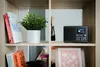 A shelf in a wooden bookcase with various items including books, a plant, and a radio. Voir les images du produit