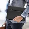 A man in a suit jacket and jeans is holding a black laptop sleeve. Anteprima dell’immagine prodotto
