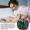 A mother and baby on a bed, with a projection alarm clock in the foreground. Produktbild-Vorschau