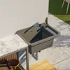 An outdoor sink mounted on a wall next to a countertop, with tiles and grass in the background. Anteprima dell’immagine prodotto