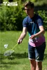 A young man playing badminton outdoors in a park. Produktbild-Vorschau