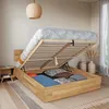 A bedroom scene with a wooden bed frame open to reveal storage space underneath, containing pillows and bedding. Produktbild-Vorschau