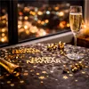 A table setting for New Year's Eve with a glass of champagne, confetti, and decorations. Anteprima dell’immagine prodotto
