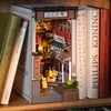 A 3D wooden book nook depicting a Japanese street scene, placed between books on a shelf. Voir les images du produit