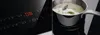 A close-up of an induction cooktop with a digital display showing settings and a pot of rice cooking on the surface. Podgląd zdjęcia produktu