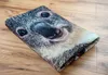 A folded towel with a koala face print is lying on a wooden surface. Podgląd zdjęcia produktu