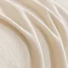 A close-up view of a textured cream-colored fabric, likely a blanket or sofa cover, showing folds and the weave of the material. Produktbild-Vorschau