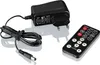 A black power adapter with a coiled black cord and a black remote control are displayed on a white background. Produktbild-Vorschau