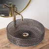 A close-up shot of a glass vessel sink with a gold faucet. Produktbild-Vorschau