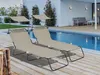 Two taupe-colored sun loungers with canopies are placed on a wooden deck next to a swimming pool. Produktbild-Vorschau