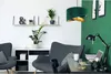 A modern living room or home office with two dark gray armchairs, a desk with a laptop and lamp, and shelves with plants and decor. Anteprima dell’immagine prodotto