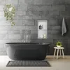 A modern bathroom with a dark bathtub, gray tiled walls, and a small stool with a plant. Náhľad obrázku produktu