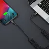 A coiled USB-C cable connects a smartphone to a laptop. Anteprima dell’immagine prodotto