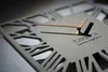 Close-up of a modern wall clock with a geometric design and Roman numerals. Náhled obrázku produktu