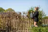 A woman is carrying a large pot in a garden. Náhľad obrázku produktu