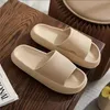 Paar beige Cloud-Slide-Sandalen mit strukturiertem Riemen auf einer Holzoberfläche neben einer Zeitschrift Náhľad obrázku produktu