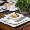 A table setting with plates, a bowl of granola, and sandwiches, with a plant in the background. Produktbild-Vorschau
