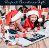 Two children wearing Santa hats are lying on a rug, looking at a Christmas advent calendar. Náhľad obrázku produktu