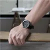 A person's arm wearing a watch is resting on a wooden surface. Produktbild-Vorschau