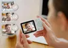 A person is holding a baby monitor that displays a baby's face. The monitor shows multiple camera feeds of the baby, indicated by 'x1', 'x2', and 'x4'. Náhľad obrázku produktu