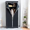 A black fabric wardrobe with its doors open, revealing clothes and shelves inside. It is placed on a patterned rug next to a white shelving unit with decorative items. Náhľad obrázku produktu