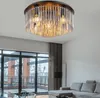 A modern living room with a large window and a sectional sofa, featuring a ceiling light fixture. Produktbild-Vorschau