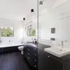 A modern bathroom with a bathtub, toilet, and vanity with a large mirror. Anteprima dell’immagine prodotto