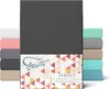 A product image showcasing a stack of folded fitted sheets in various colors, with a prominent dark gray sheet in the foreground and a branded label. Produktbild-Vorschau