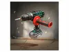 A cordless drill with an auxiliary handle is shown in a dynamic, action-oriented pose, with drill bits and debris appearing to fly around it. Podgląd zdjęcia produktu
