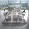 A bed with plaid bedding is set up in a modern room with large windows overlooking a scenic landscape. Produktbild-Vorschau